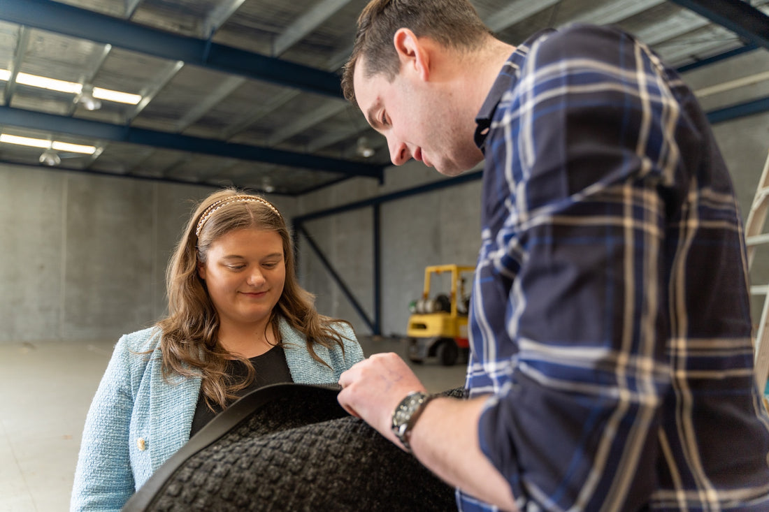 Two people inspecting a large black object in an industrial setting.