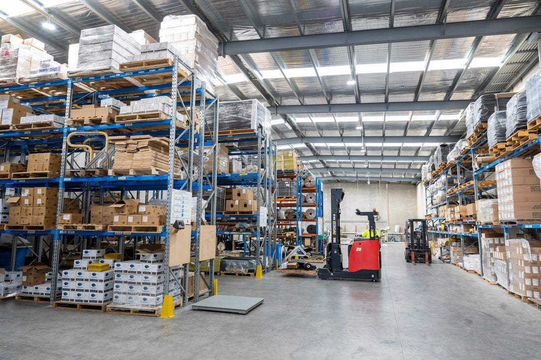 Warehouse interior with shelves stocked with boxes and forklifts.